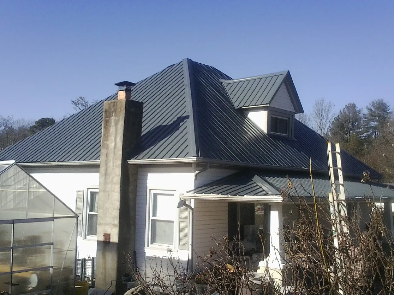 Dark blue standing seam metal roof on a white farmhouse with dormer — Slate & Tile Roof Repair by Roofing Brothers in Beardsley