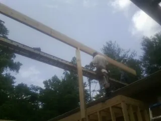 Carpenter setting a ridge beam over a new addition frame — Ice Dam Removal by Roofing Brothers in Beardsley
