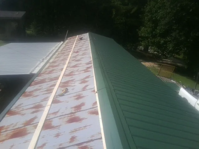 Old rusted panels beside newly installed green metal roofing — Wind Damage Roof Repair by Roofing Brothers in Beardsley