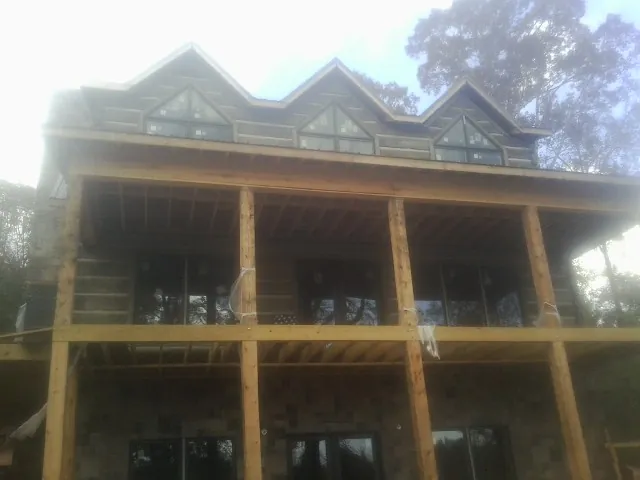 Dormers and porch framing on a large log home under construction — Roof Coating work by our crew in Beardsley