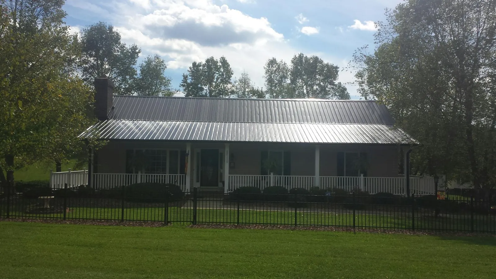 Gray metal roof on a brick ranch with a full width front porch — Gutter Guard Installation work by our crew in Beardsley