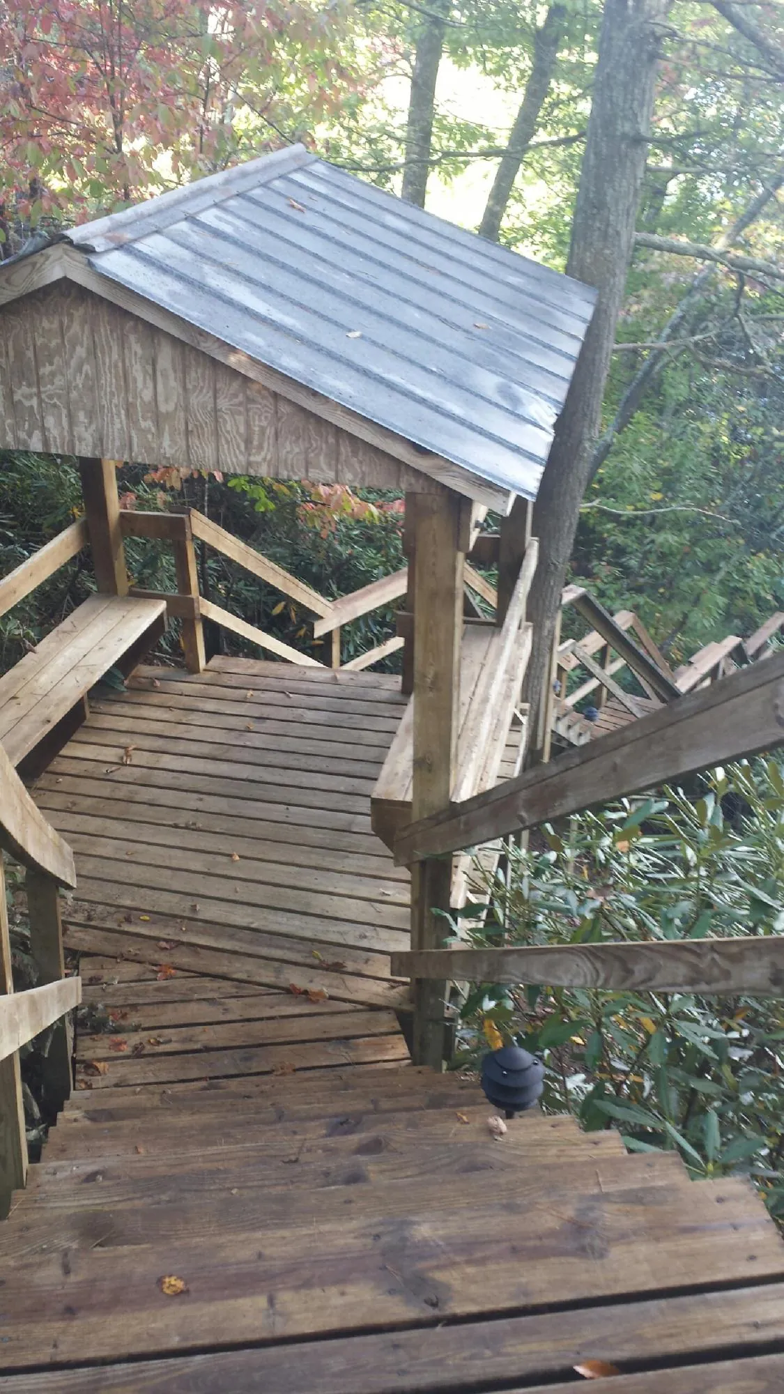 Metal roofed shelter over wooden steps on a wooded walkway — Skylight Repair & Installation work by our crew in Beardsley
