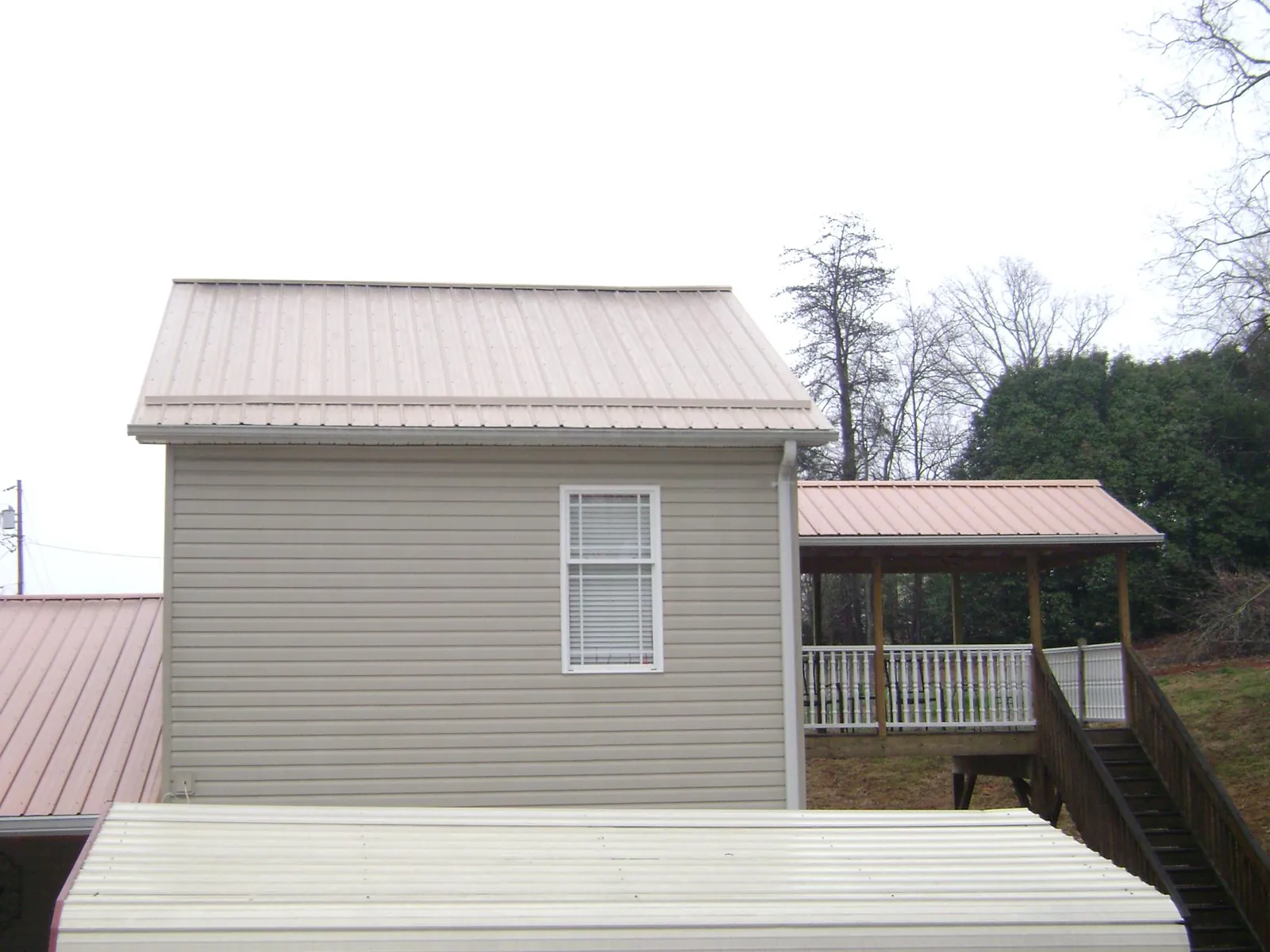 Tan metal roofs on a two story addition and attached porch, from a Roof Replacement job in Beardsley